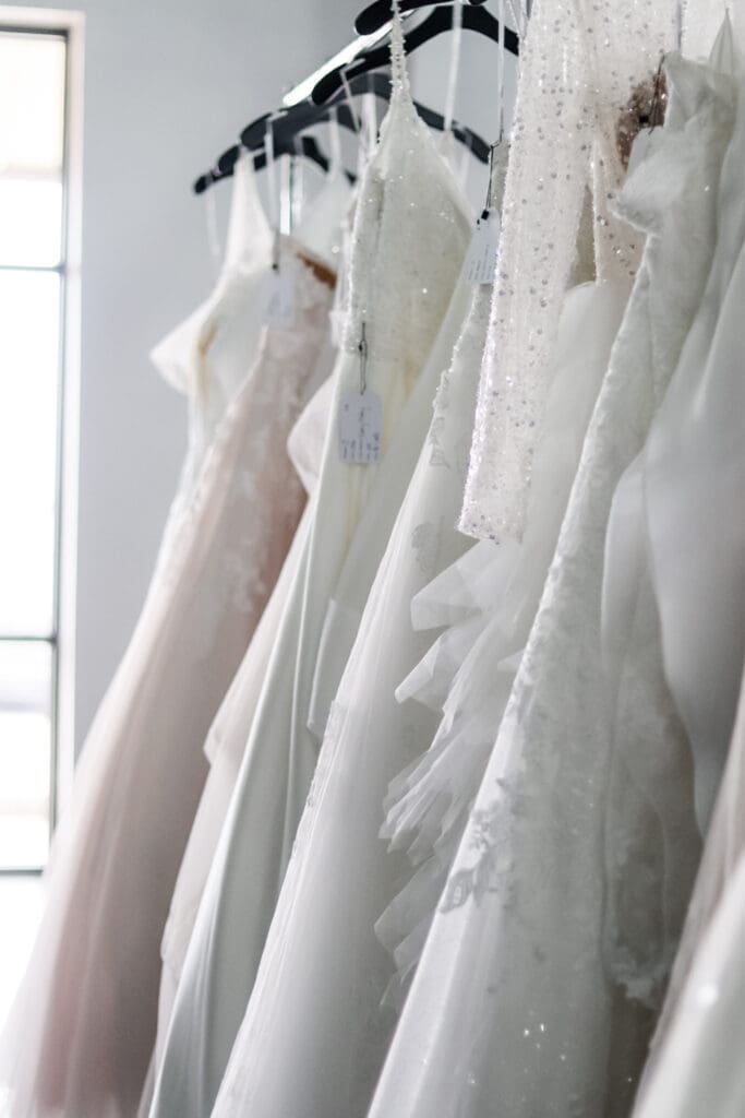 Collection of elegant wedding dresses hanging in Austin bridal boutique for luxury dress shopping with Olive & Eden Weddings