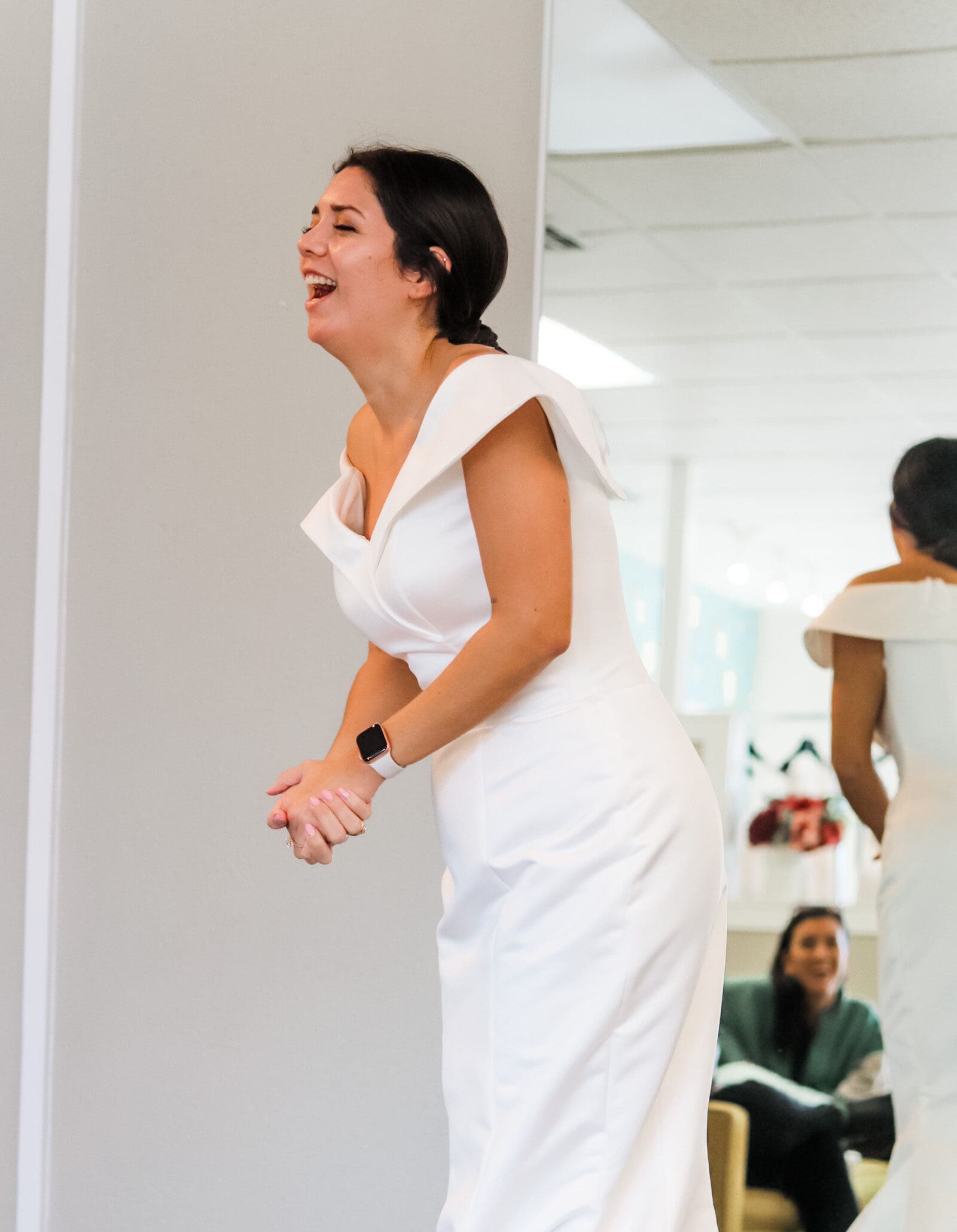 Ecstatic bride laughing in off-shoulder wedding gown during joyful dress fitting in Austin bridal boutique with Olive & Eden Weddings