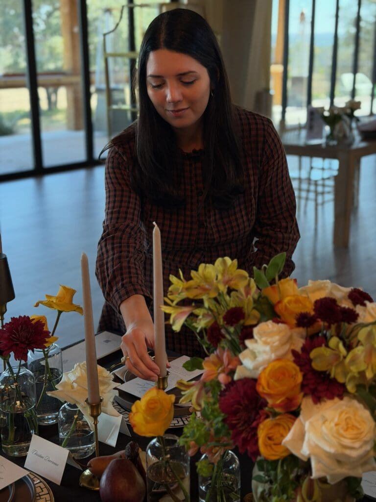 Austin wedding planner Lauren adjusting taper candles for a luxury moody tablescape setup.