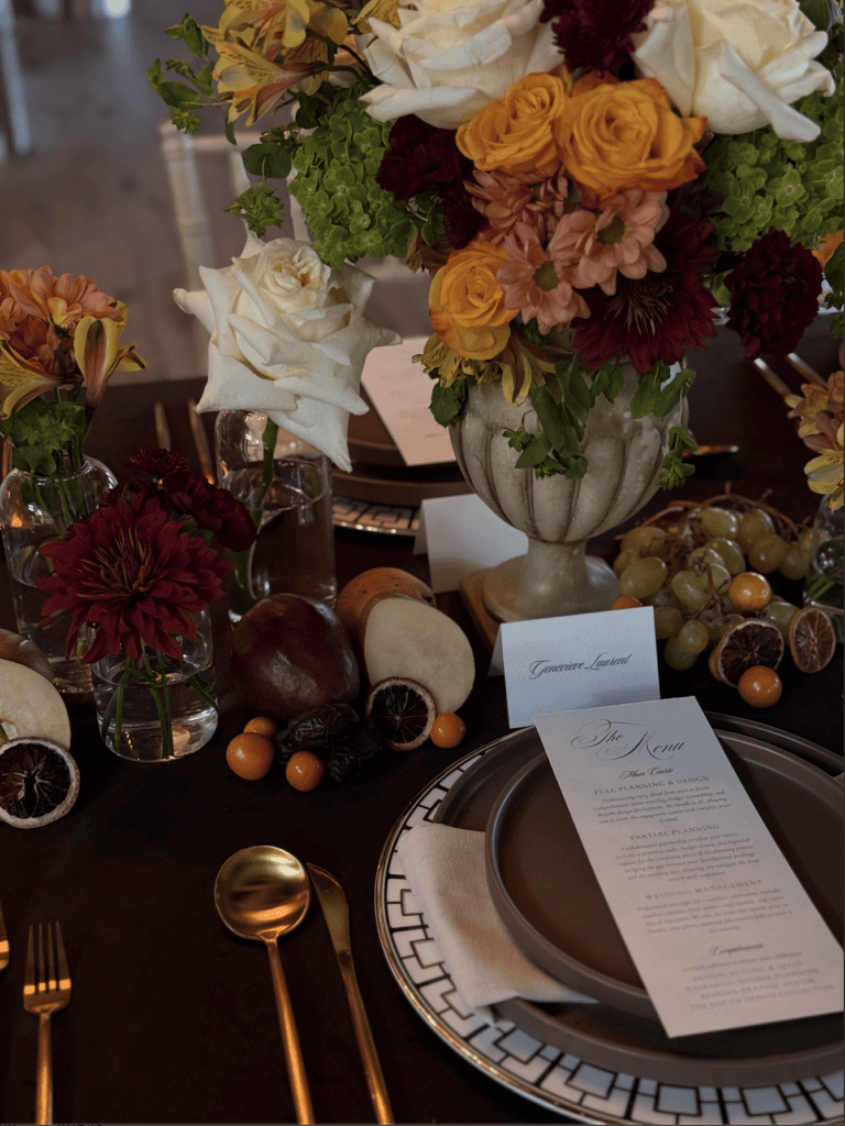 Vertical detail shot of vintage floral urn, dried citrus, fresh fruit accents, and bespoke wedding menu card designed by Austin wedding planner Olive & Eden.