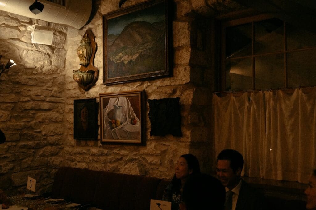 A dark, moody corner of Alla Campagna featuring historic limestone walls and curated vintage paintings for an editorial reception.