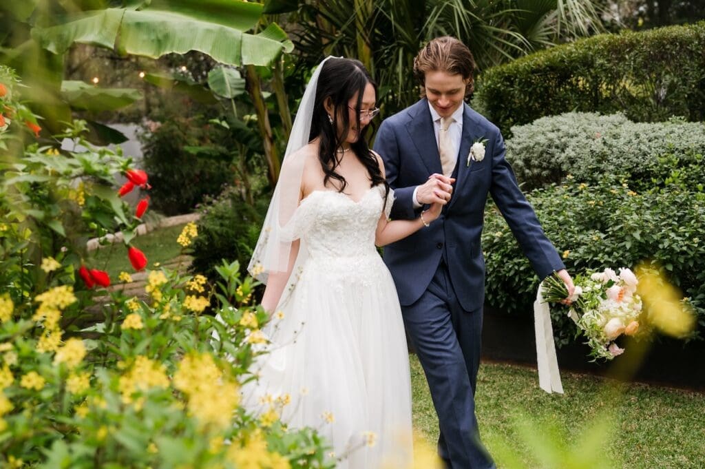 Candid wedding photography of a bride and groom strolling through blooming gardens in the Texas Hill Country.