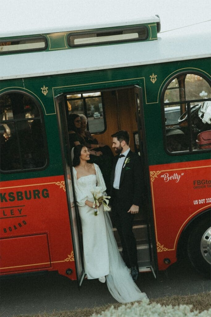 A modern bride and groom standing by a vintage green trolley in the Texas Hill Country.